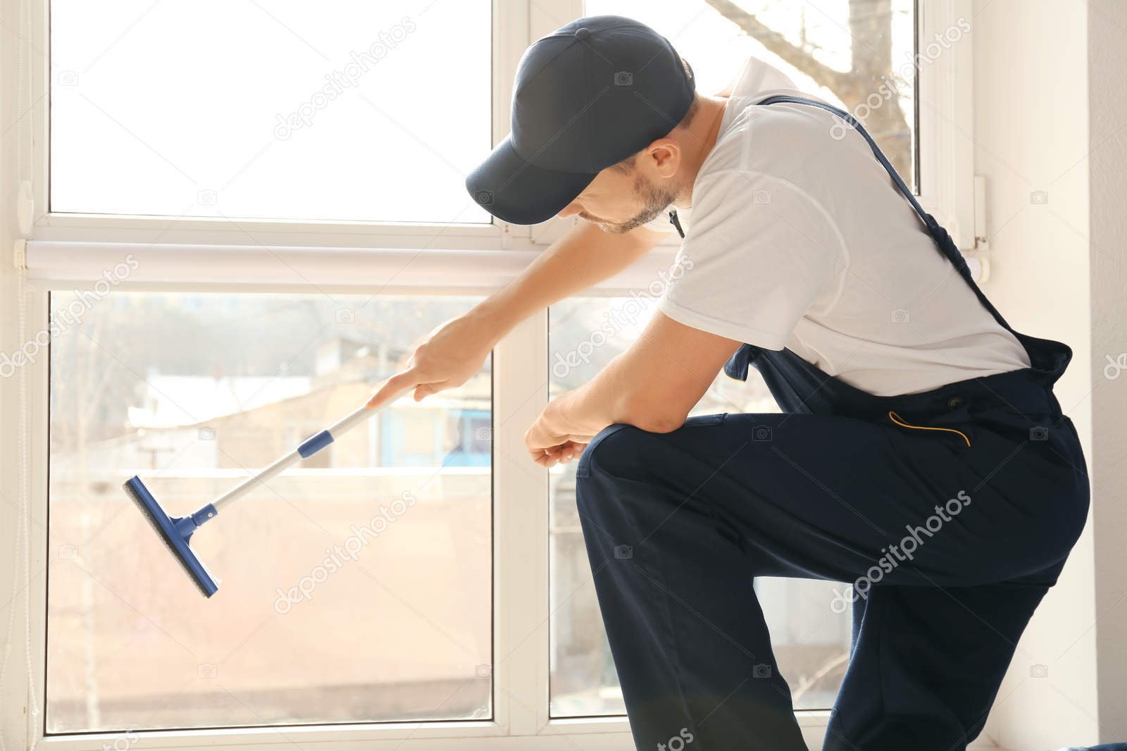 Young man washing window in office
